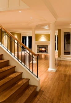Wide plank, light natural-finish hardwood flooring Nashville covering a spacious, open-concept living and dining area with clean white walls and large glass doors leading to the exterior.