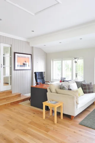A bright and modern living room with light wooden floors, white walls, and comfortable seating.