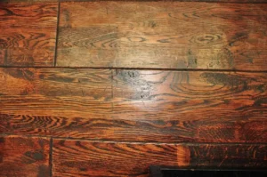 A high-angle, close-up shot of polished, dark-stained hardwood flooring. Two yellow forensic evidence markers labeled "2" and "4" are placed on the floor. To the right, a clipboard with white paper and a black pen sits on the wood.